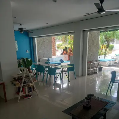 a living room with a table and chairs and a large window at Baan Oui guest house - Nai Harn in Phuket Town