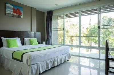 a bedroom with a large bed and a large window at Baan Oui guest house - Nai Harn in Phuket Town