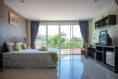a bedroom with a bed and a tv and a balcony at Baan Oui guest house - Nai Harn in Phuket Town