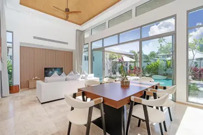 a dining room with a table and chairs and a couch at SHAMBHALA GRAND Pool Villas x MonthStayZ Thailand in Phuket Town