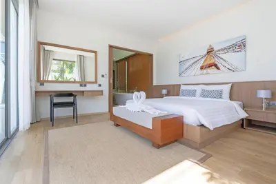 a bedroom with a bed and a desk and a window at SHAMBHALA GRAND Pool Villas x MonthStayZ Thailand in Phuket Town