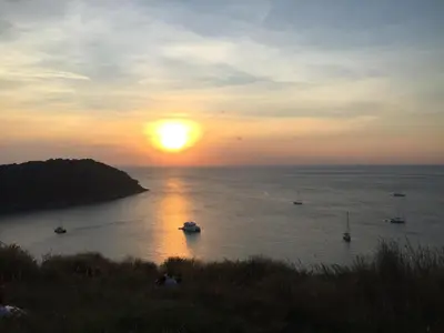 a sunset over a body of water with boats at RAWAÏ Bedroom and kitchen in Rawai Beach