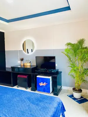 a bedroom with a blue bed and a tv at BH Baan Paradise Hotel Patong in Patong Beach