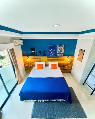 a bedroom with a large bed with blue walls and orange pillows at BH Baan Paradise Hotel Patong in Patong Beach