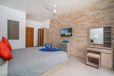 a bedroom with a bed and a tv on a brick wall at Sabai Villas, 7 min drive from Naiharn & Rawai, Private pool, Four villas available in Rawai Beach