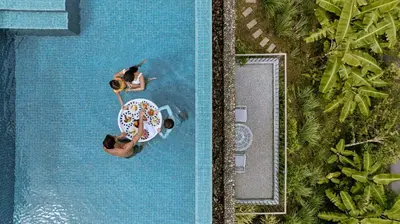 an overhead view of two people in a pool with an umbrella at COMO Point Yamu, Phuket in Ban Pa Khlok