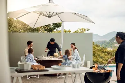 a group of people sitting around a table with an umbrella at COMO Point Yamu, Phuket in Ban Pa Khlok