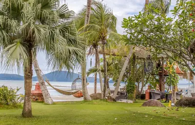 a hammock between palm trees on a beach at Royal Thai Villa Phuket - SHA Extra Plus in Rawai Beach
