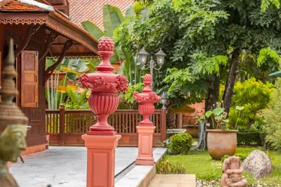 a group of red pillars in a garden at Royal Thai Villa Phuket - SHA Extra Plus in Rawai Beach