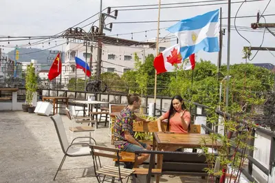 a man and a woman sitting at a table with flags at The Auto Place in Ban Sam Kong