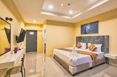 a bedroom with a bed and a desk and a television at TJ Patong Hotel - Otop Shopping Paradise in Patong Beach