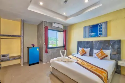 a bedroom with two beds and a window at TJ Patong Hotel - Otop Shopping Paradise in Patong Beach