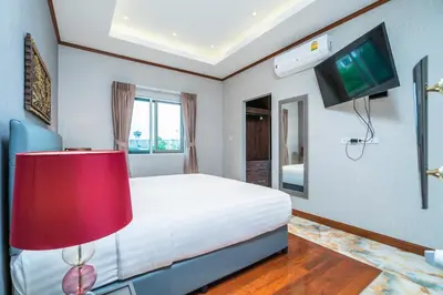 a bedroom with a bed with a red lamp and a tv at Villa Stan in Kamala Beach