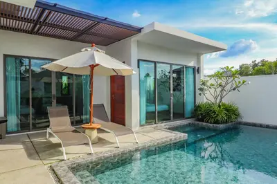 a pool with two chairs and an umbrella next to a house at Shambhala grand villa by Cozy Lake in Bang Tao Beach