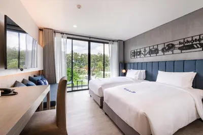 a hotel room with two beds and a desk at Kokotel Phuket Nai Yang Beach in Nai Yang Beach