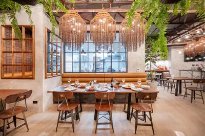 a dining room with tables and chairs and chandeliers at Kokotel Phuket Nai Yang Beach in Nai Yang Beach