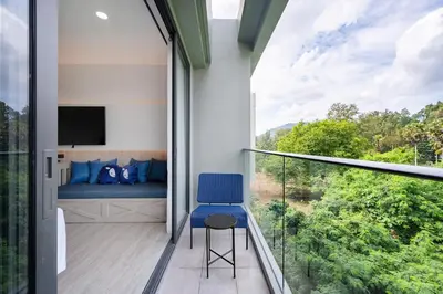 a bedroom with a blue chair and a bed on a balcony at Kokotel Phuket Nai Yang Beach in Nai Yang Beach