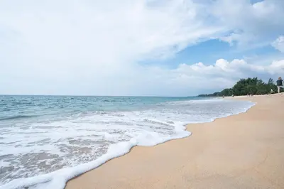 a beach with the ocean and people on it at Kokotel Phuket Nai Yang Beach in Nai Yang Beach