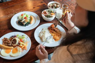 a woman sitting at a table with plates of food at Kokotel Phuket Nai Yang Beach in Nai Yang Beach
