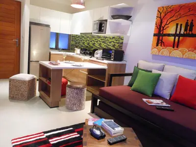 a living room with a couch and a kitchen at Top Floor, One-Bedroom Apartment in Phuket Town