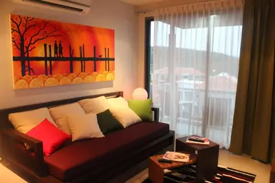 a living room with a couch and a painting on the wall at Top Floor, One-Bedroom Apartment in Phuket Town