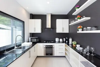 a kitchen with white cabinets and a black wall at Villa White Pool in Kamala Beach