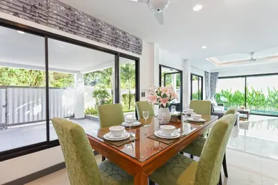 a dining room with a wooden table and chairs at Villa White Pool in Kamala Beach