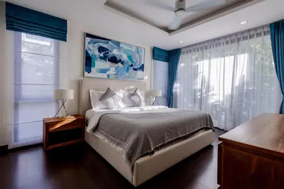 a bedroom with a large bed with blue curtains at Hot! Laguna Park 5BR Modern Pool Villa - Bangtao Beach in Bang Tao Beach