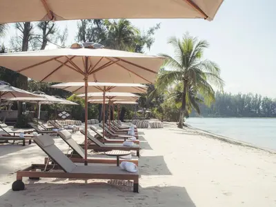 a row of lounge chairs and umbrellas on a beach at Anantara Layan Phuket Resort in Layan Beach