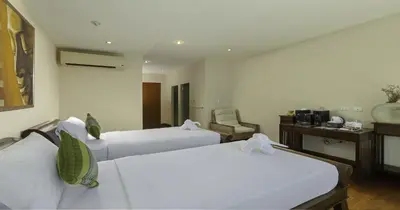 a hotel room with two beds and a desk at Villa Yoosook in Patong Beach