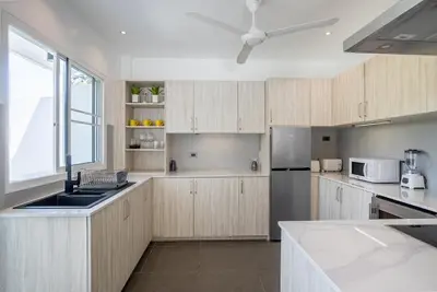 a kitchen with wooden cabinets and a ceiling fan at Villa Ayan, Amazing Pool, 2 bedrooms Near Nai harn Beach in Rawai Beach