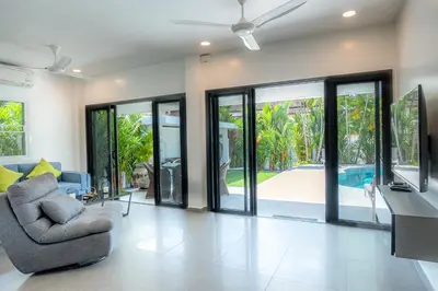 a living room with sliding glass doors and a chair at Villa Ayan, Amazing Pool, 2 bedrooms Near Nai harn Beach in Rawai Beach