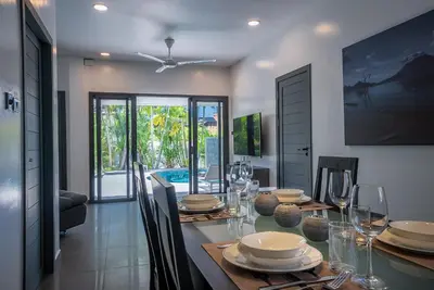 a dining room with a table with plates and wine glasses at Villa Ayan, Amazing Pool, 2 bedrooms Near Nai harn Beach in Rawai Beach