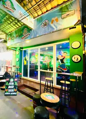 a restaurant with a bar with stools in front of it at Popeyes Hostel Patong in Patong Beach