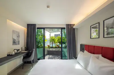 a bedroom with a bed and a desk and a window at Travelodge Phuket Town in Phuket Town