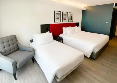 a hotel room with two beds and a chair at Travelodge Phuket Town in Phuket Town