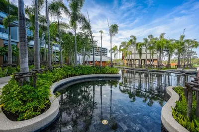 a pool of water with palm trees in front of a building at Suite Vela 1BR Infinity Pool Mida Grande Surin in Surin Beach