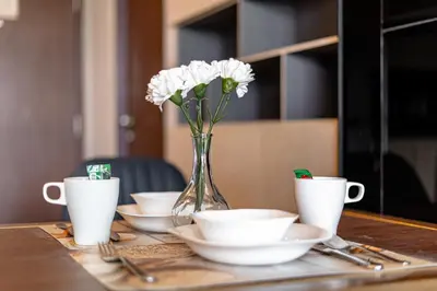 a vase of flowers sitting on a table with cups at Suite Calista 2BRView JacuzziMida Grande Surin in Surin Beach