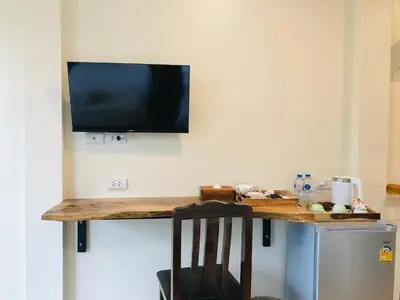 a desk with a television on a wall with a chair at Koh Yao Yai Sea Breeze House เกาะยาวใหญ่ซีบรีซเฮ้าส์ in Ko Yao Yai