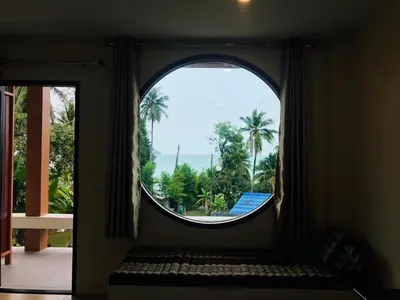 an arched window with a view of palm trees at Koh Yao Yai Sea Breeze House เกาะยาวใหญ่ซีบรีซเฮ้าส์ in Ko Yao Yai