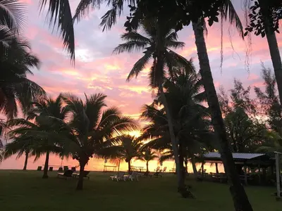a sunset at the beach with palm trees at Koh Yao Yai Sea Breeze House เกาะยาวใหญ่ซีบรีซเฮ้าส์ in Ko Yao Yai