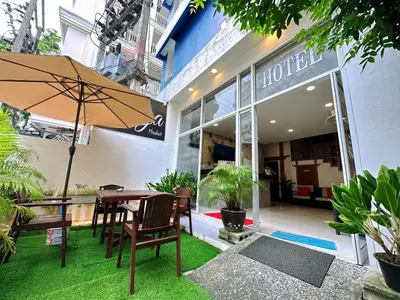 a table and chairs with an umbrella in front of a hotel at Hotel Baya Phuket in Patong Beach