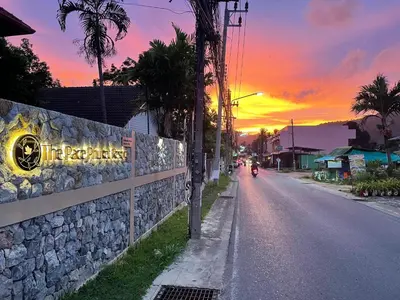a street with a sunset in the background at The Pace Phuket Boutique Resort in Rawai Beach
