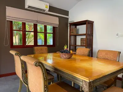 a dining room table with chairs and a bowl of fruit on it at The Pace Phuket Boutique Resort in Rawai Beach