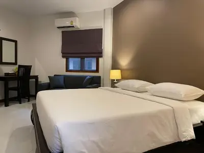 a bedroom with a white bed and a living room at The Pace Phuket Boutique Resort in Rawai Beach