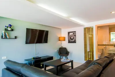a living room with a couch and a tv on the wall at Hallo Patong Hotel in Patong Beach