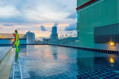a woman standing next to a swimming pool on a building at Hallo Patong Hotel in Patong Beach