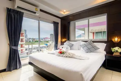 a bedroom with a large bed with a large window at Hallo Patong Hotel in Patong Beach