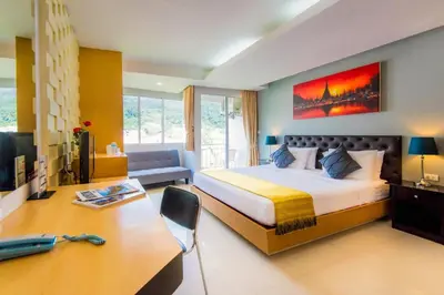 a hotel room with a bed and a desk and a desk at Hallo Patong Hotel in Patong Beach