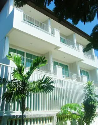a white building with a white fence and palm trees at The Mareeya Place in Kamala Beach